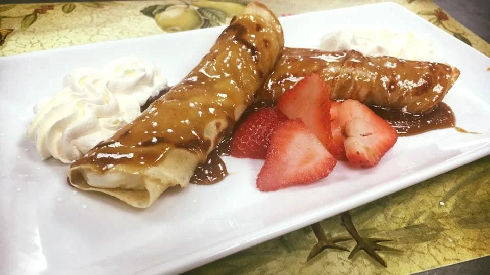Breakfast crepes with caramel sauce, fresh strawberries and whipped cream