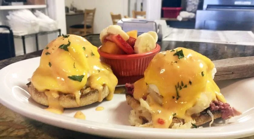 Eggs Benedict with hollandaise and a side of fresh fruit at Red Rooster Marco